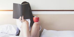 mujer leyendo un libro en la cama con una taza de te