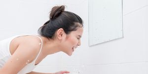Side View Of Beautiful Woman Washing Face In Bathroom