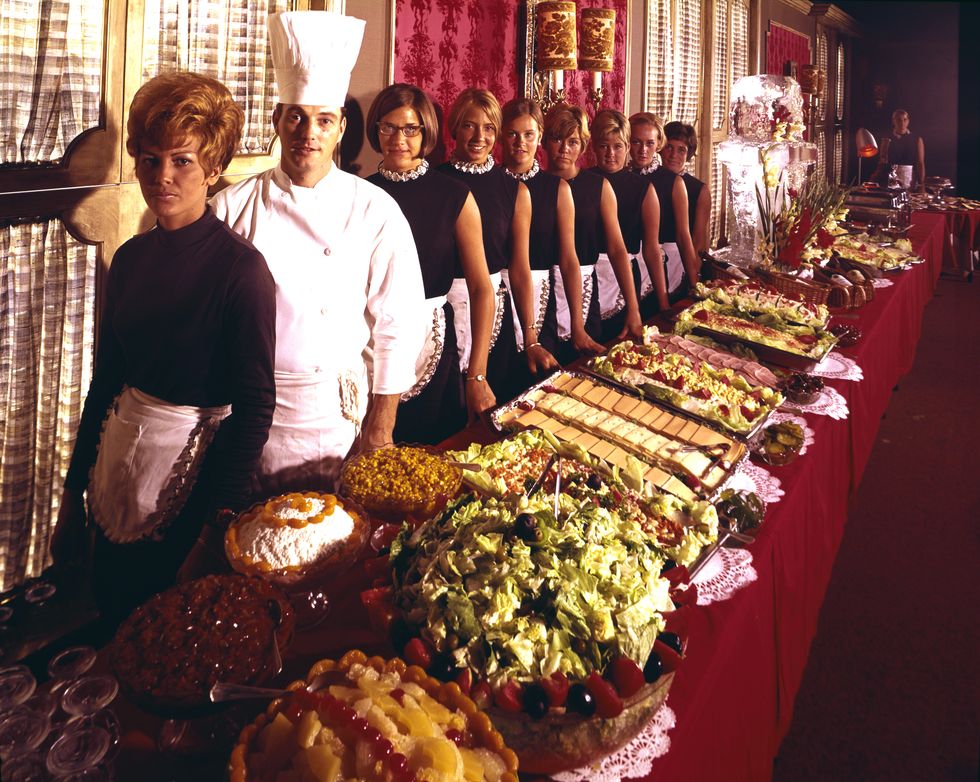 a line of uniformed waitresses and a cook pose behind a long buffet table at the beach plaza hotel, ocean city, maryland, 1960s photo by aladdin color incgetty images