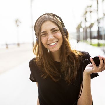 Portrait of happy young woman on boardwalk listening to music