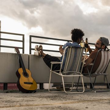 Young couple with beer and guitar sitting on rooftop