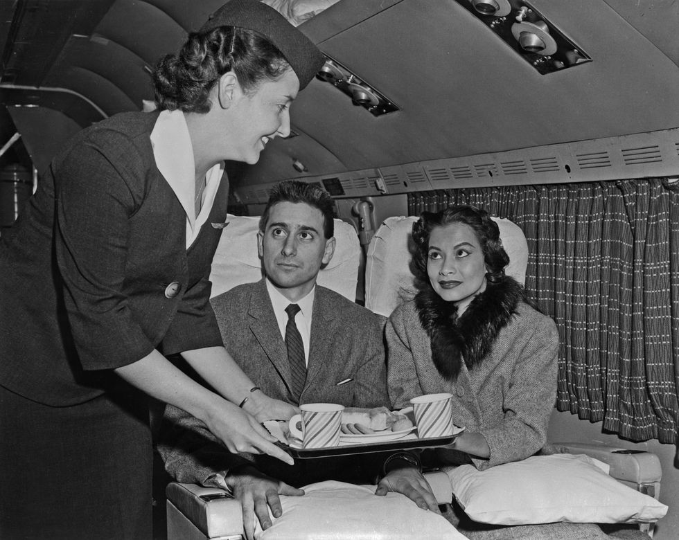 new york   mid 1950s  an air hostess serves a snack to passengers on a transocean air lines boeing 377 stratocruiser in the mid 1950s transocean air lines flew between 1946 and 1962 and was a pioneer discount airline photo by michael ochs archivegetty images