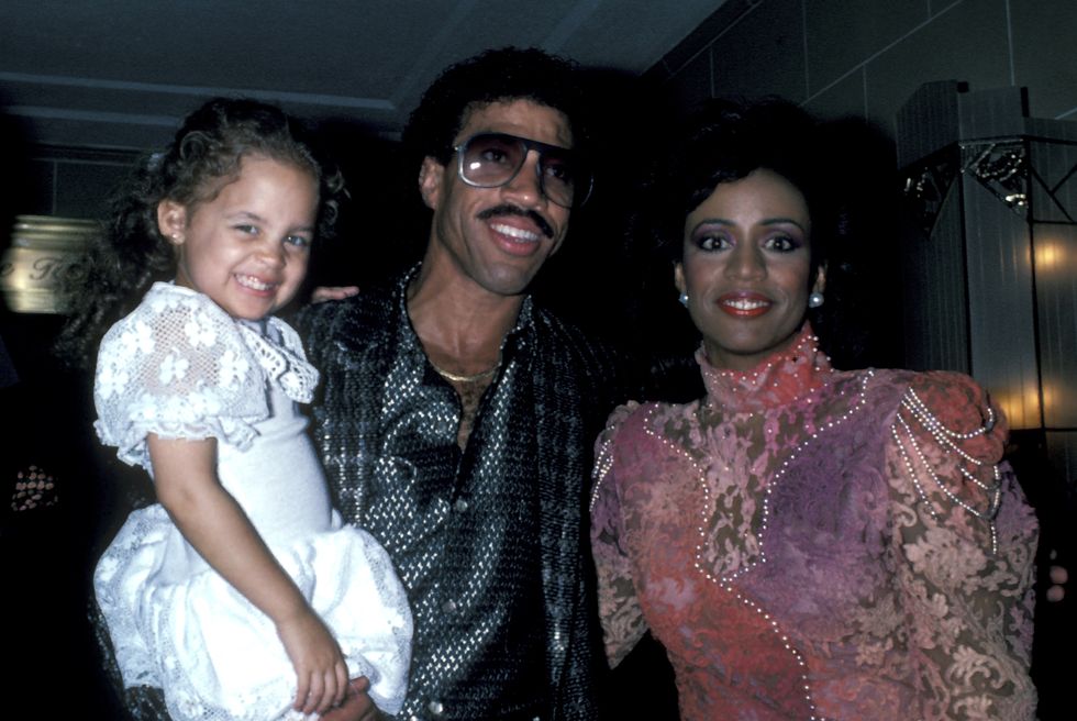 nicole richie, lionel richie and brenda harvey richie, lionel is holding a young nicole, all three are smiling