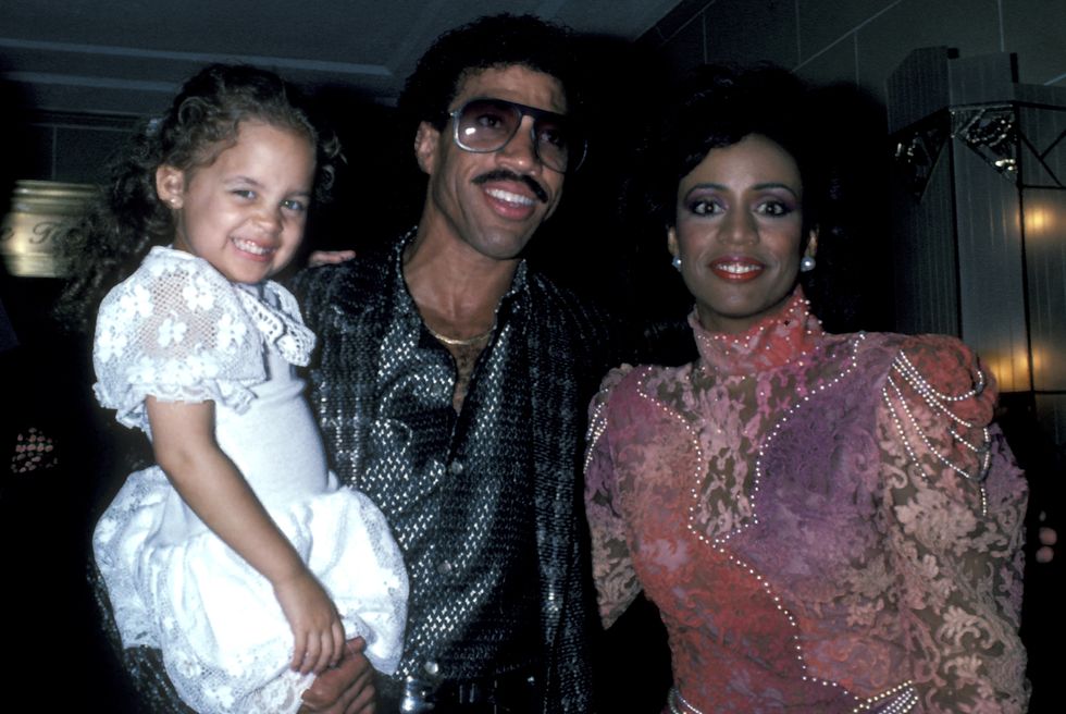 nicole richie, lionel richie and brenda harvey richie, lionel is holding a young nicole, all three are smiling