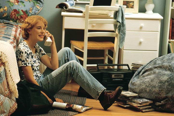 chica sentada en el suelo de su habitación con un teléfono antiguo ellees