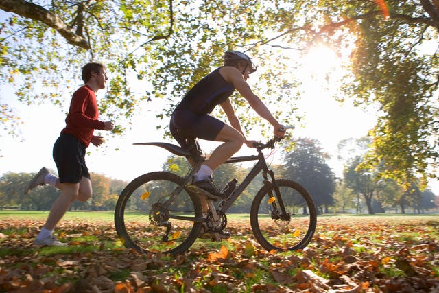 a man riding a bike on a path with another man watching