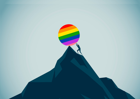 man rolling a rainbow colored ball up a hill