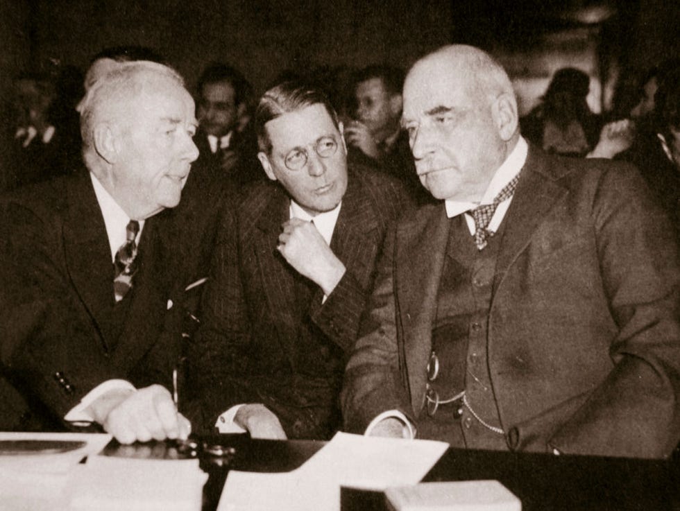 three men in business suits sit together and talk