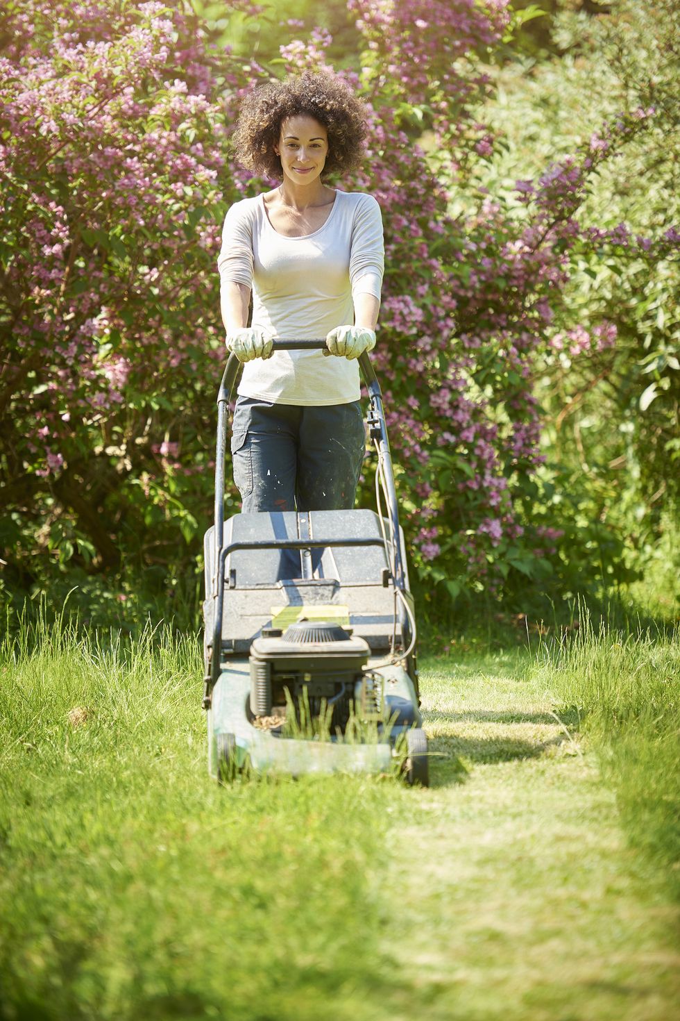 a woman is mowing the lawn