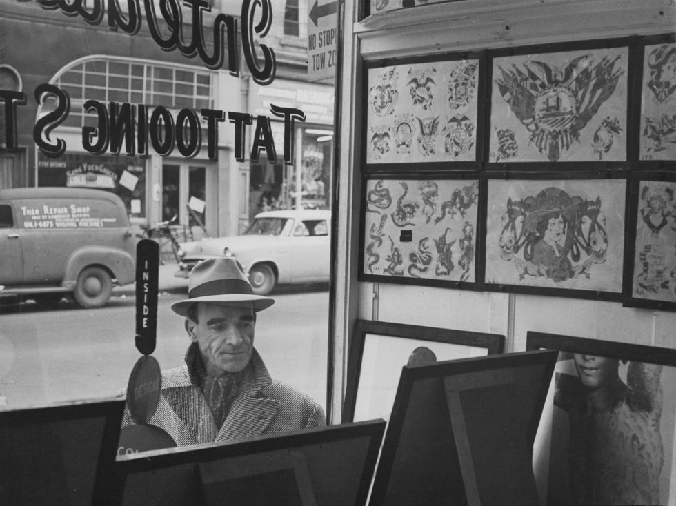 french writer auguste le breton 1913   1999 researches his crime novels in the more dangerous areas of montreal, canada, circa 1955 here he peers into a tattoo parlour photo by keystone featureshulton archivegetty images