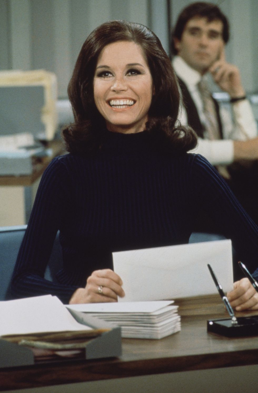 american actress and commediene mary tyler moore as mary richards smiles broadly as she sits at a desk in a scene from the mary tyler moore show also known as mary tyler moore, los angeles, california, 1970 photo by cbs photo archivegetty images