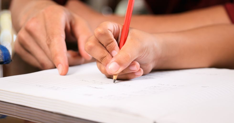 Elementary Girl Doing Homework Hand Writing On Exercise Book