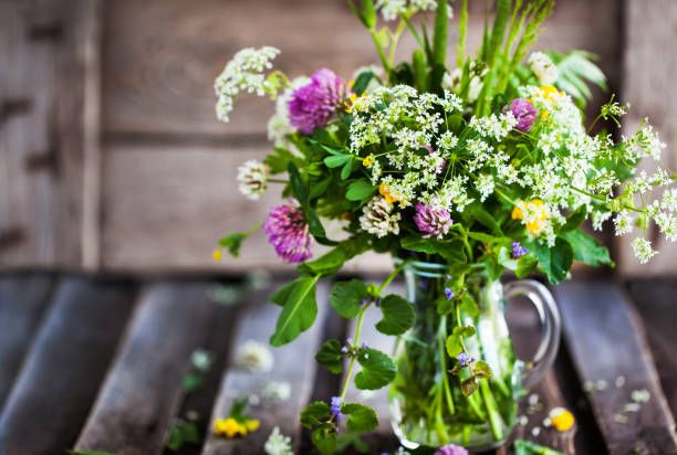 bouquet of wildflowers in glass jar on wooden table, summer concept