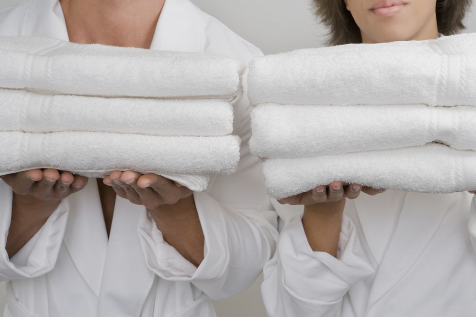 mid section view of a mid adult man with a young woman holding stacks of folded towels