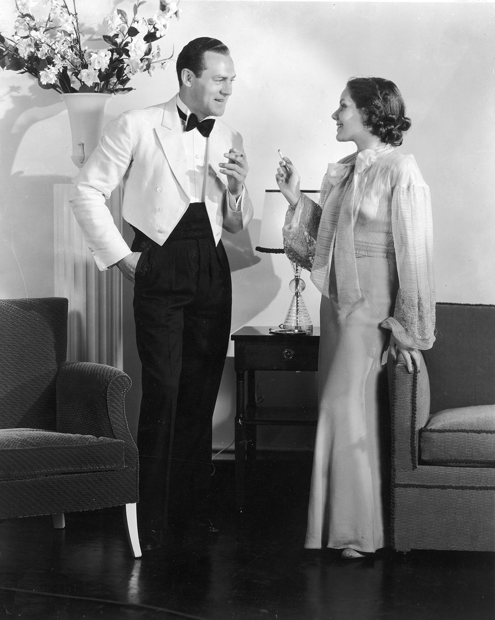 pareja bien vestida fumando un cigarro, años 30