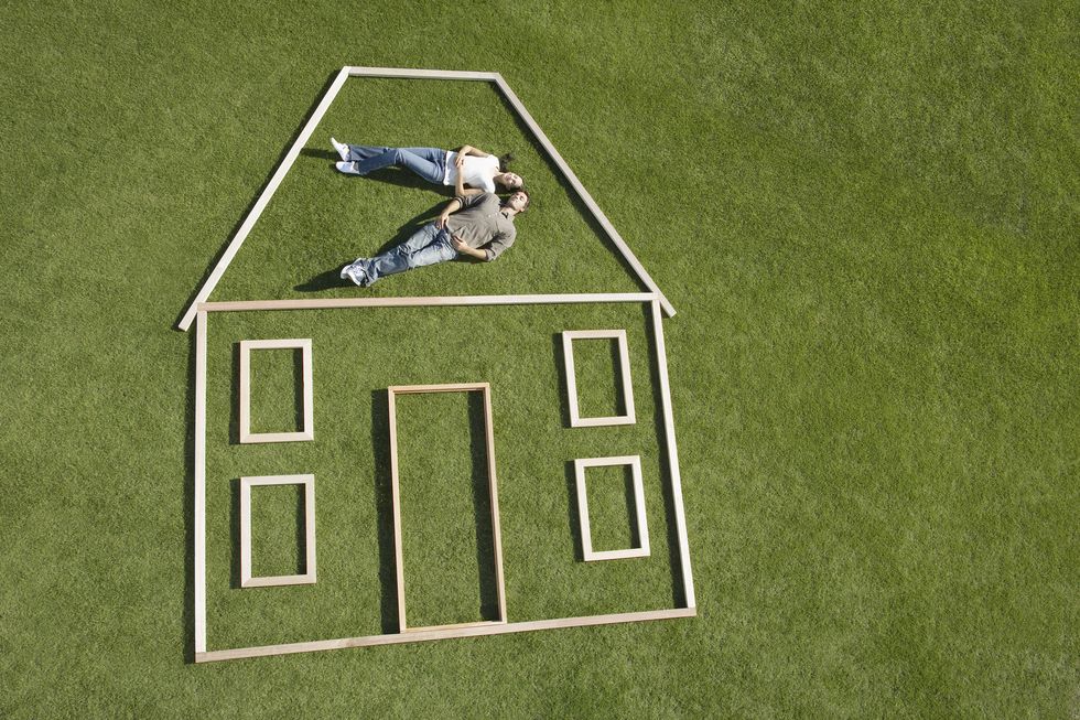 couple lying on grass inside wooden house outline