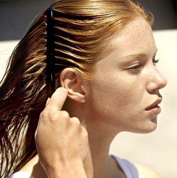 young woman combing her hair, outdoors