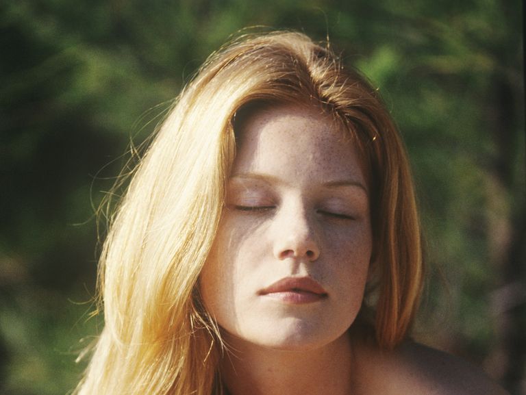 Portrait of a young woman sitting outdoors, sunbathing