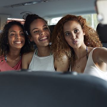 young women smiling and making selfie in the backseat of car