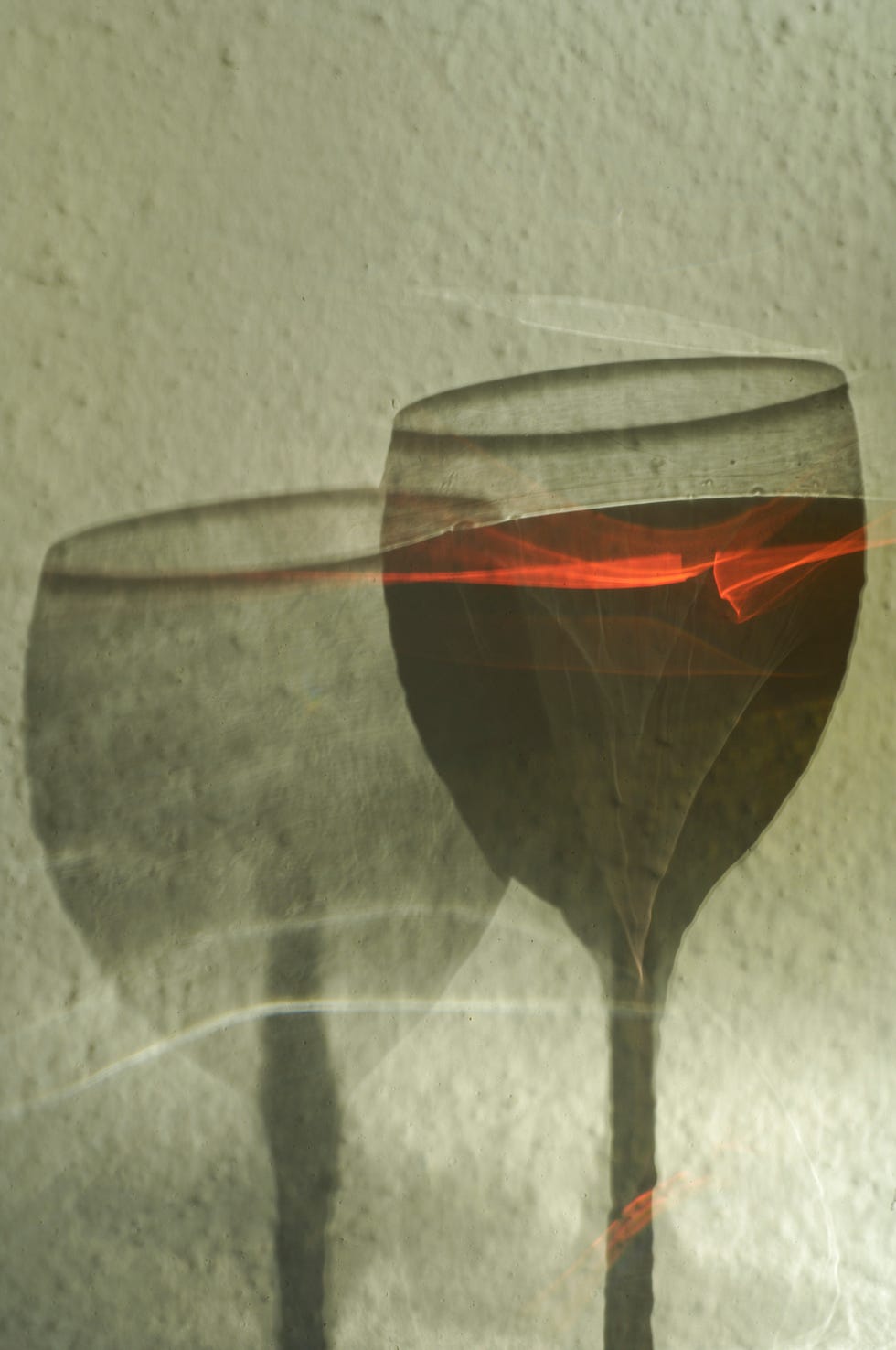 shadows of full and empty wine glasses on textured wall