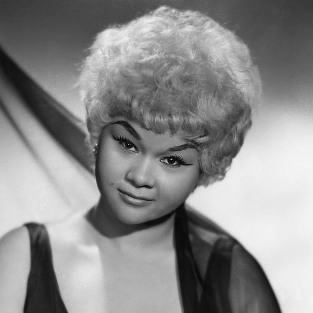 etta james looks at the camera, she wears a sleeveless outfit with a sheer wrap hanging on one shoulder