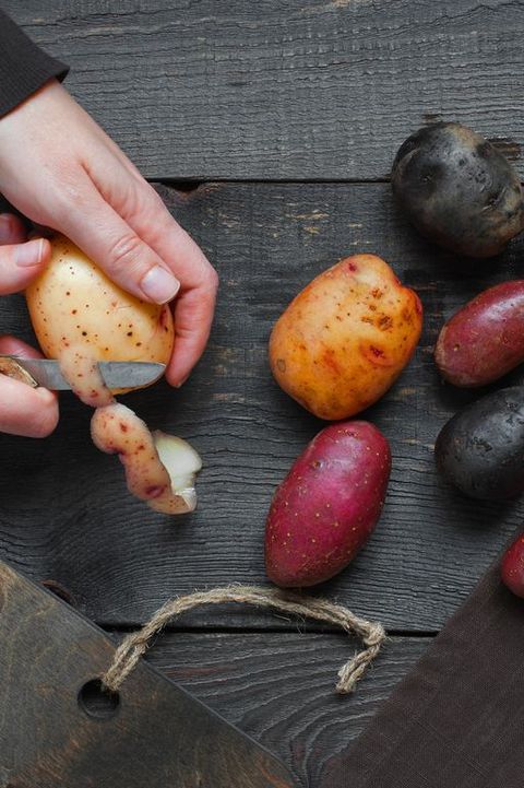 Female hands peel the fresh potatoes