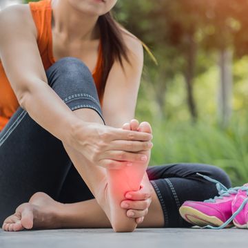 vrouw grijpt naar haar pijnlijke voet na het hardlopen