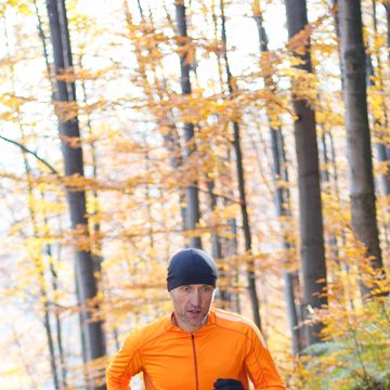 Male runner running on trail through autumn forest in mountains