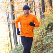 Male runner running on trail through autumn forest in mountains