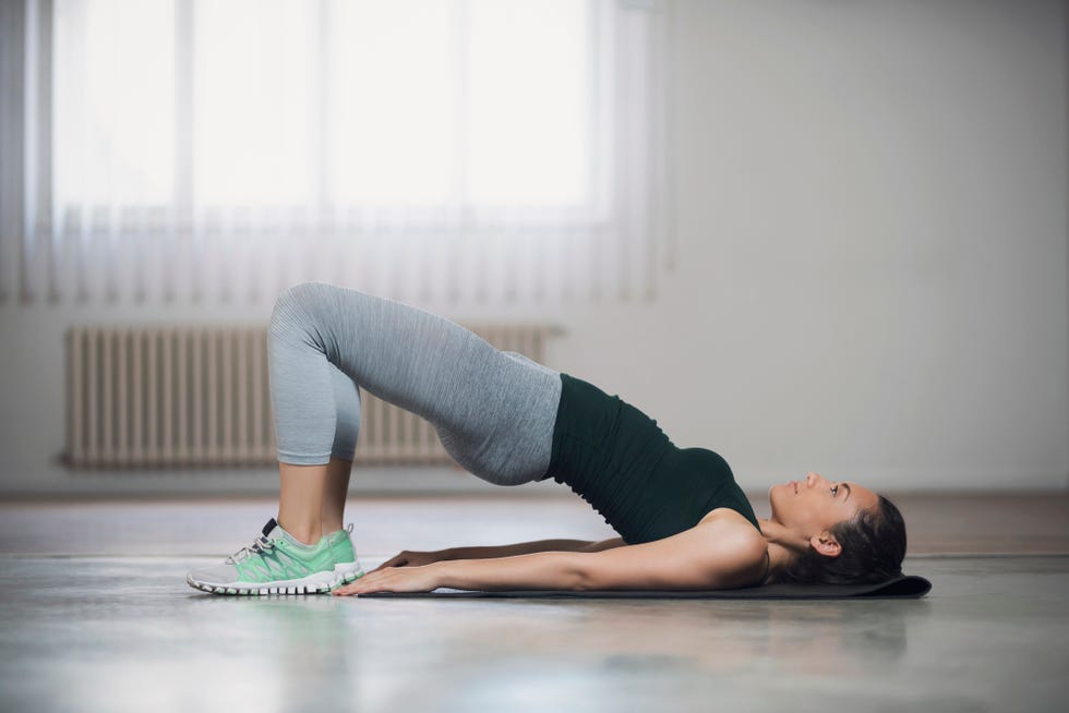 beautiful young woman doing hip lifts on the floor