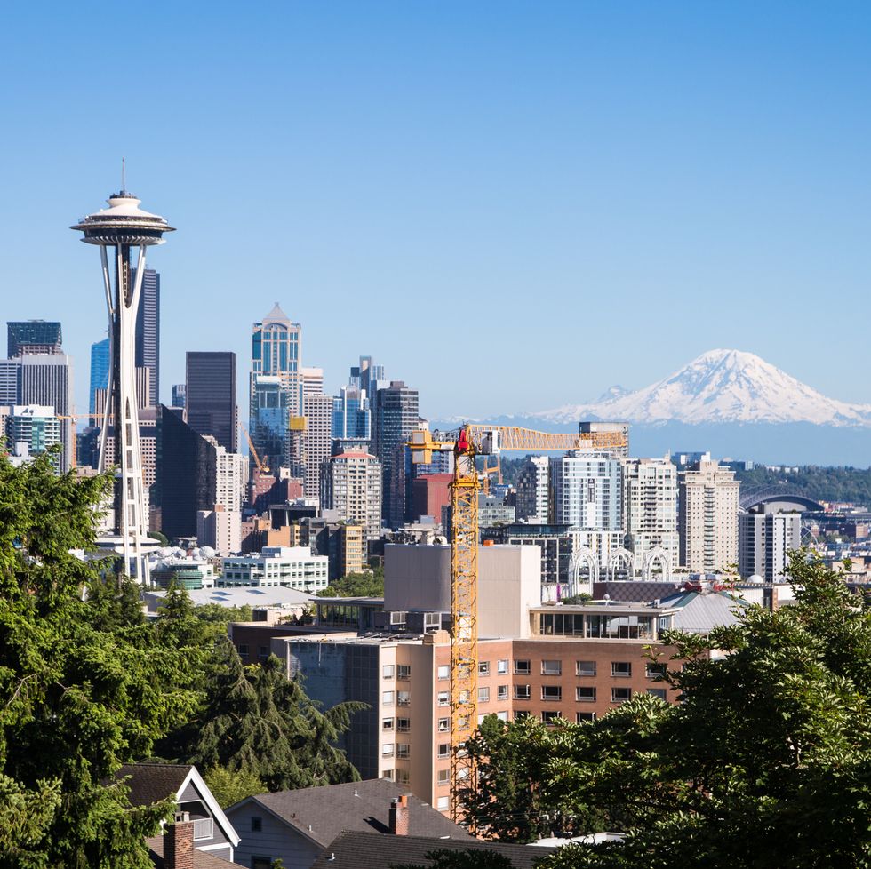 a classic view of seattle downtown district with the famous space needle tower and the mount rainier snow covered mountain in the background in washington state, usa