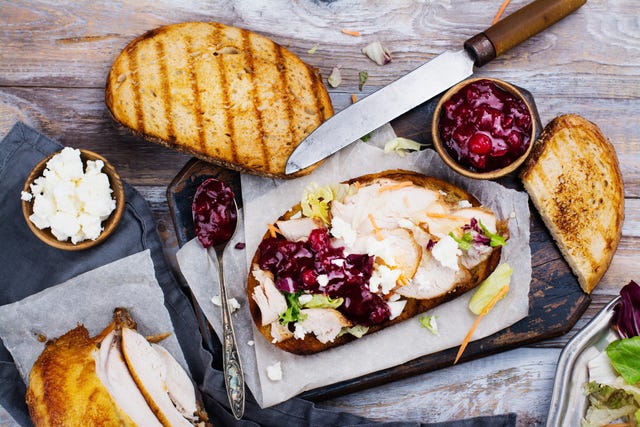 homemade leftover thanksgiving day sandwich with turkey, cranberry sauce, feta cheese and vegetables top view
