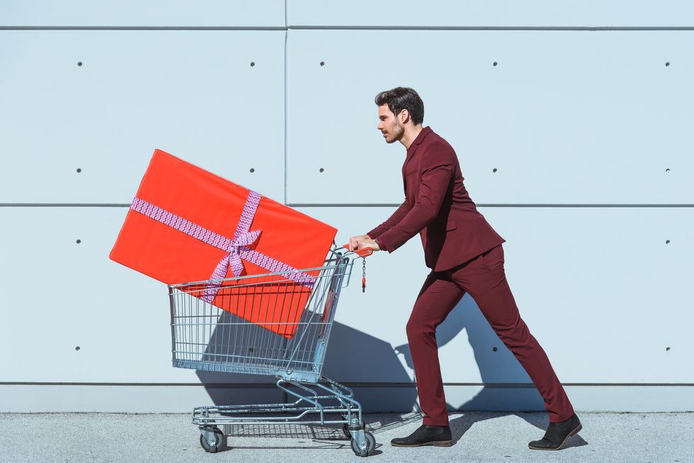 man pushing shopping cart with big red gift box