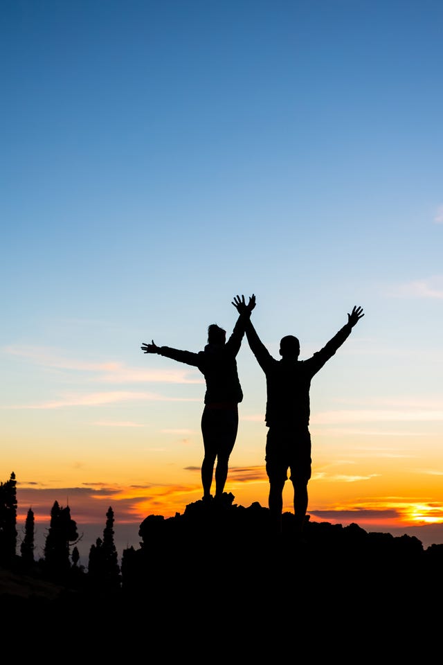 Teamwork couple climbing and reaching mountain peak Teamwork couple climbing and reaching mountain peak