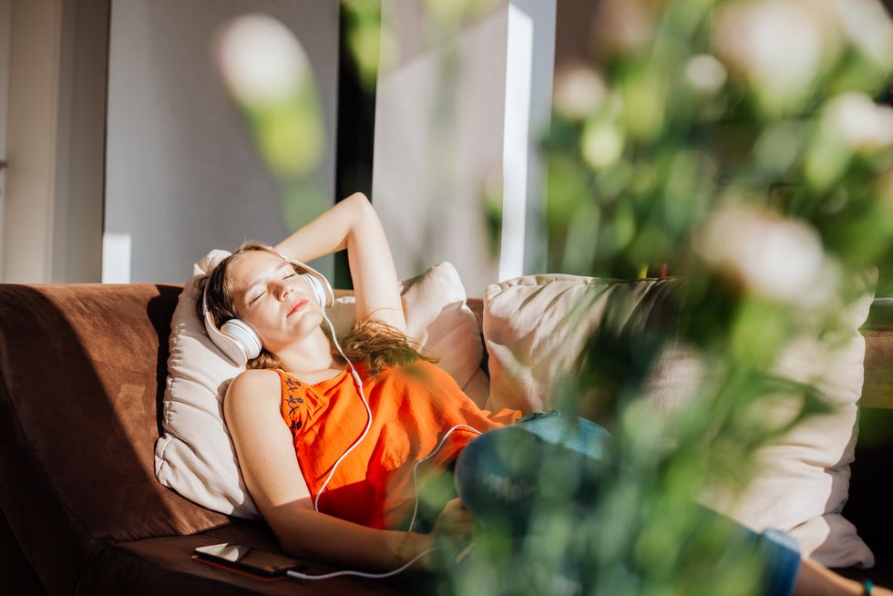 woman relaxing in sunlight, listening to music, indoor