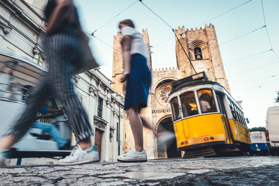 O tradicional eléctrico amarelo desce a Rua Augusto Rosa em direcção à Sé de Lisboa, com turistas a atravessar a rua