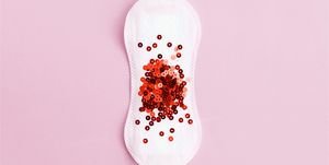 Menstrual pad with red glitter on pastel background