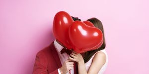 couple kissing behind balloons
