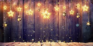 Glowing Christmas Stars Hanging At Rustic Wooden Background
