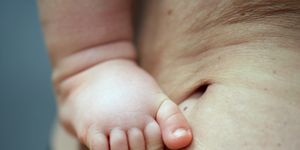 cropped close up of a baby's right foot pressed against the abdomen of an older person