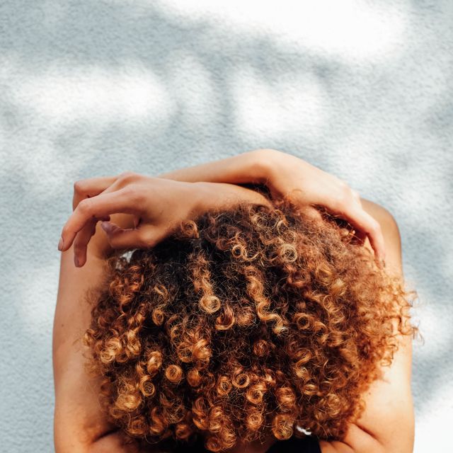 rear view of woman with curly hair against wall