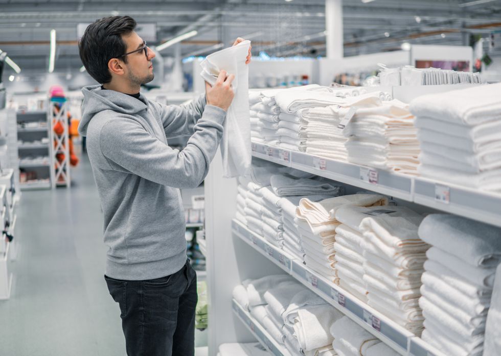 male customer inspecting and buying towels in supermarket white clean towels
