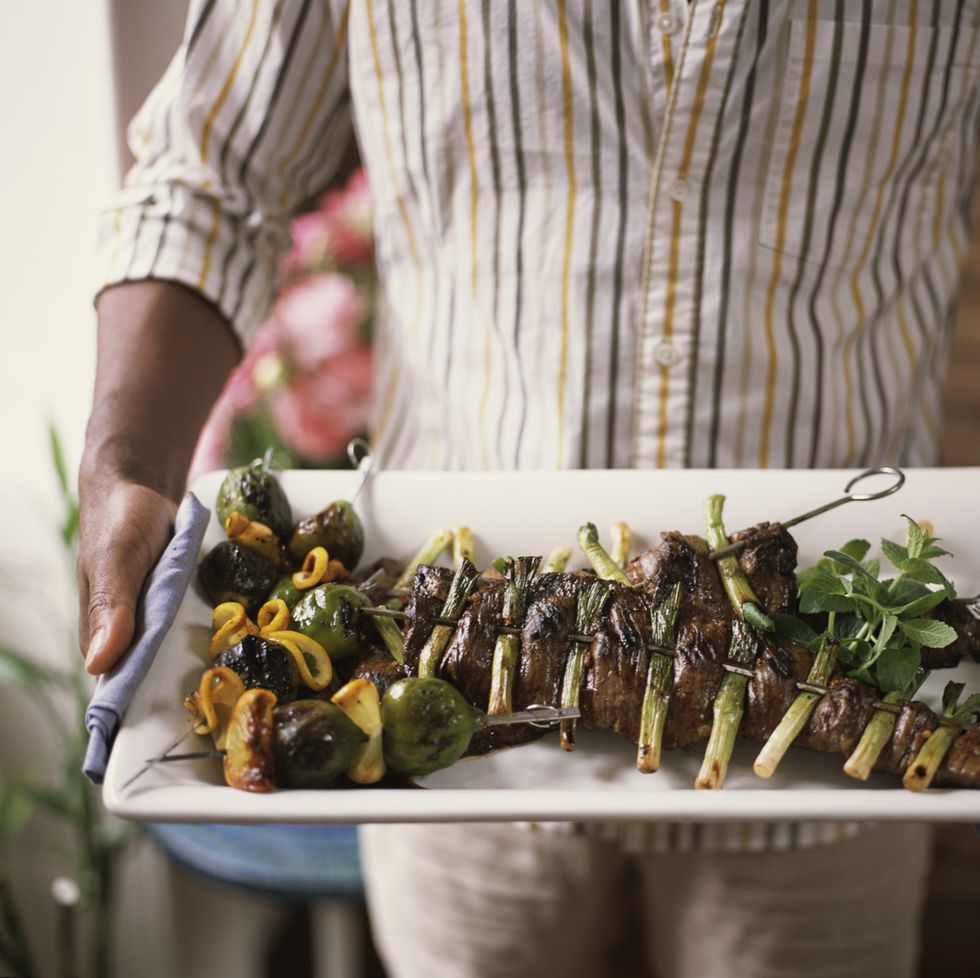 man serving a tray of healthy grilled foods men's health