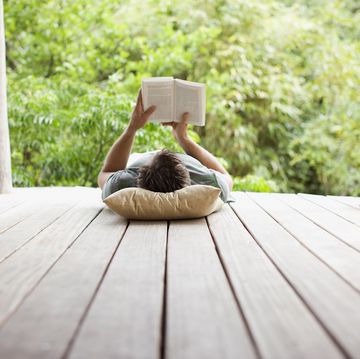 a person lying on a mat reading a book