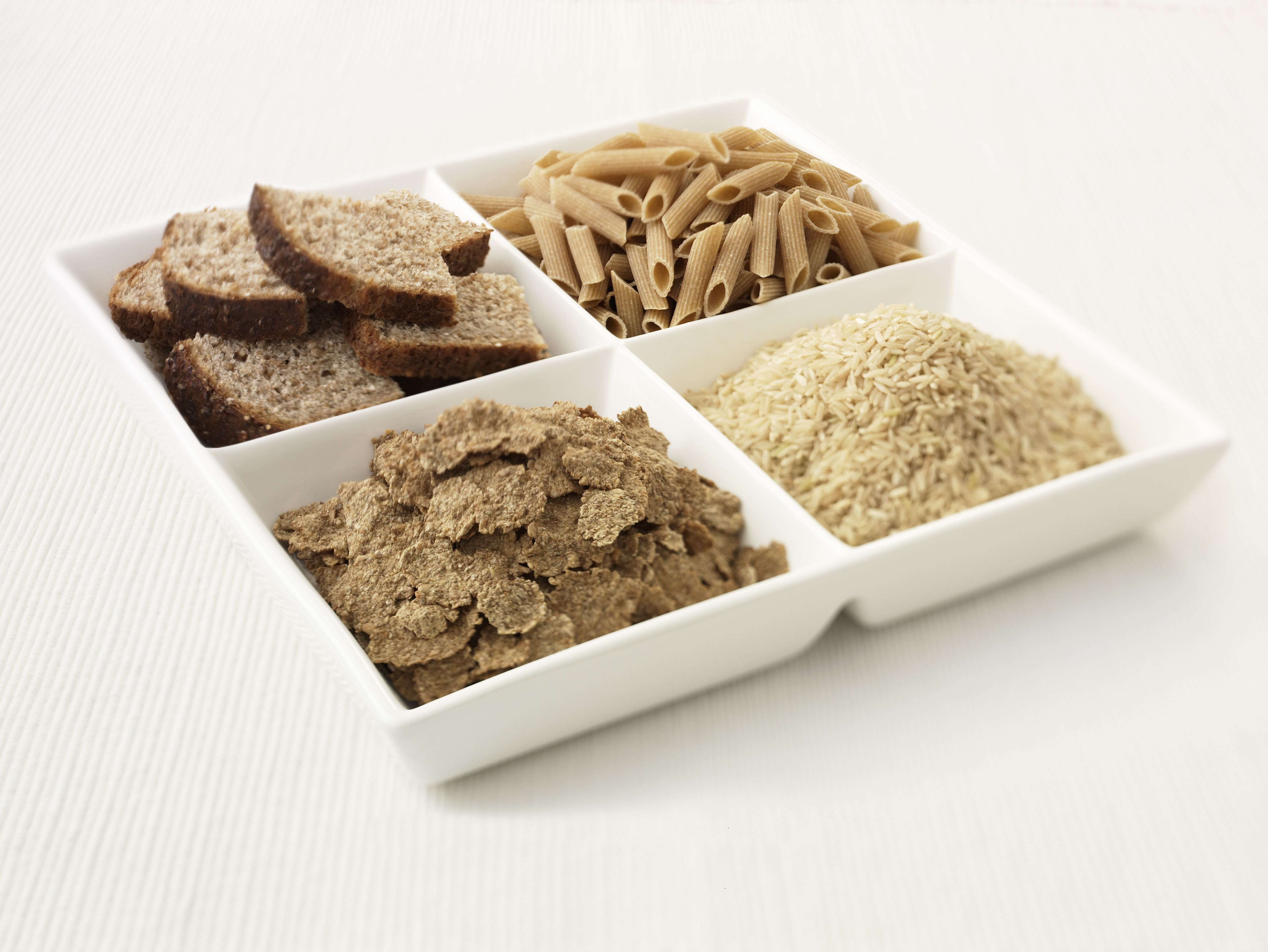 Close up of sectioned plate with bread, pasta, rice and cereal