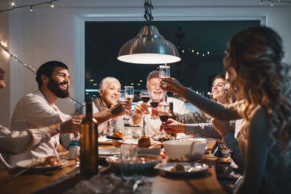 closeup side view of a family having a christmas eve dinner they are having some traditional roast, gravy and vegetables and also some vegetarian food there are three men and four women at the table having casual conversation