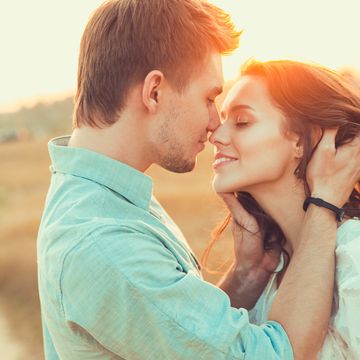 Young couple in love outdoor.in summer in field. Couple hugging. Young beautiful couple in love staying and kissing on the field on sunset. Soft sunny colors.