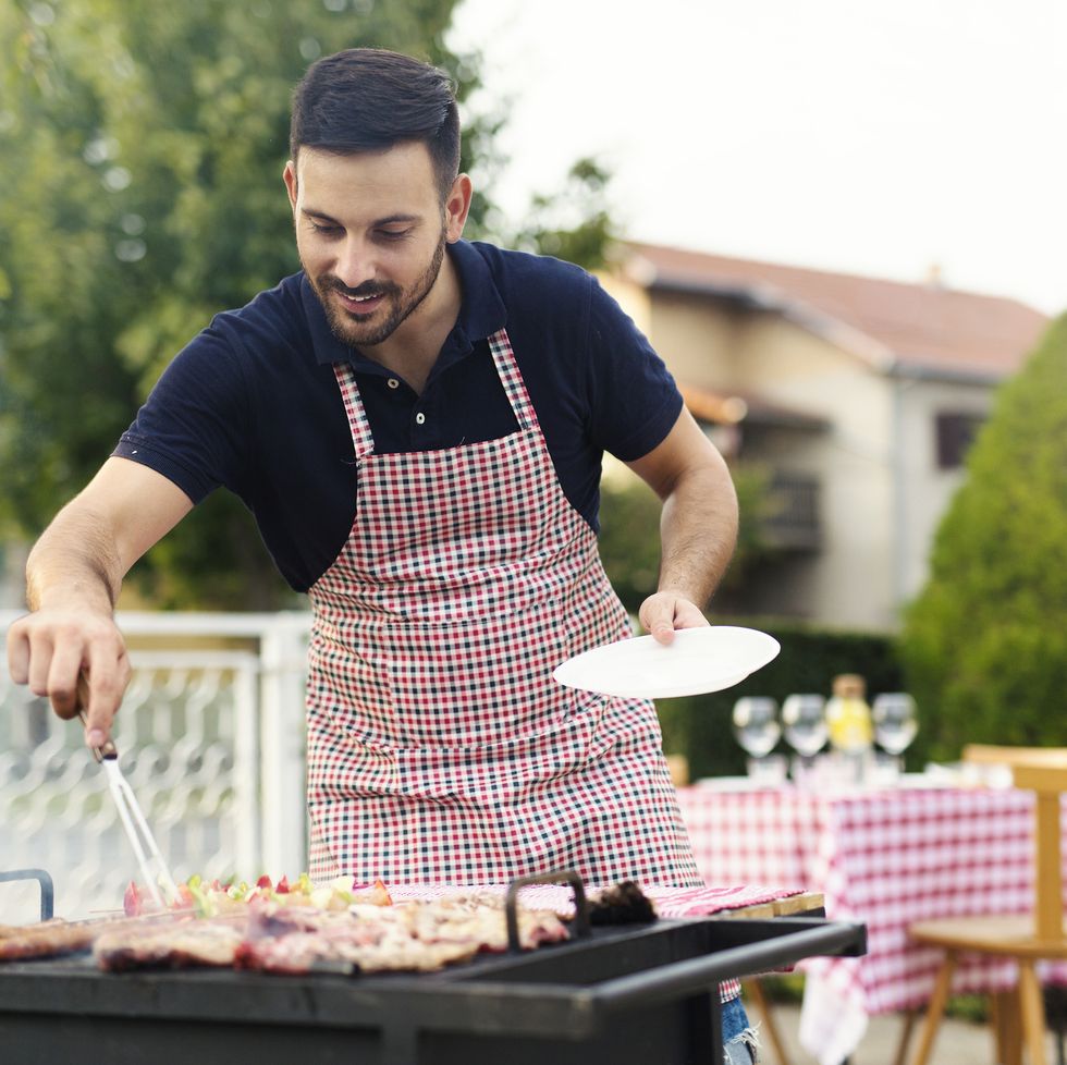 man preparing meat on the grill in his backyard