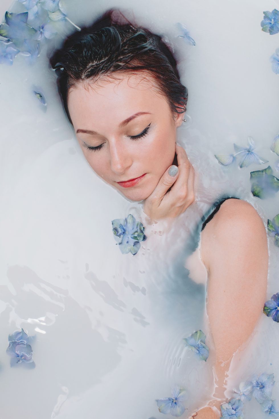 Woman lying in a milky bath with flowers