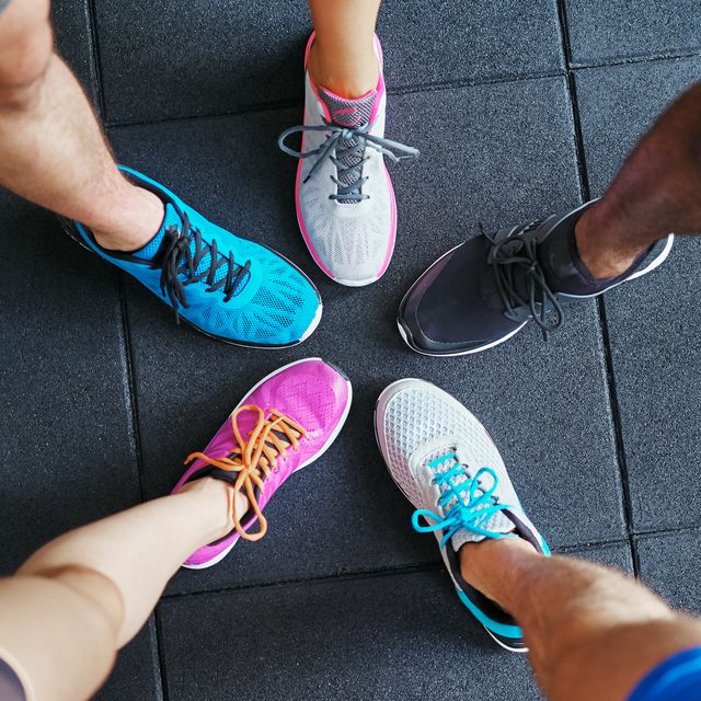 high angle of a group of sporty peoples feet wearing running shoes standing together in a huddle on a gym floor